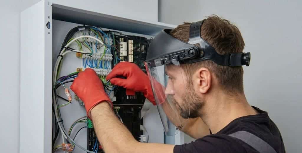 Technician performing electrical maintenance while wearing PPE